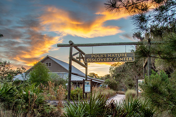 Landscape view of Discovery Center building and signage with sunset background.