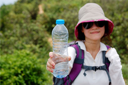 Woman in outdoor setting holding an empty water bottle